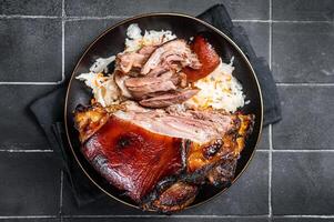 Roast Pork Ham Hock, knuckle with Sauerkraut on a plate. Black background. Top view photo