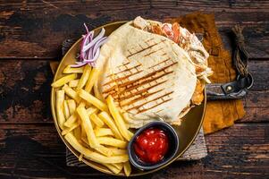 Doner kebab, Shawarma in grilled pita bread with vegetables, meat and french fry. Wooden background. Top view photo