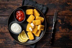 Fried Fish Sticks Fingers with sauce in a plate. Wooden background. Top view photo