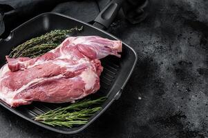 Ready for cooking lamb whole shoulder, raw leg meat on a grill pan with spices. Black background. Top view. Copy space photo