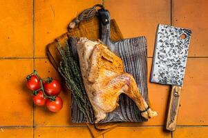 Grilled guinea fowl with herbs and spices on butcher board, cooked game bird. Orange background. Top view photo