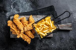 Chicken breast strips with French Fries and Ketchup. Black background. Top view photo