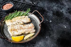 Roast Fillets of codfish, cooked cod fish meat. Black background. Top view. Copy space photo