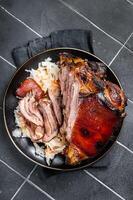 Roast Pork Ham Hock, knuckle with Sauerkraut on a plate. Black background. Top view photo