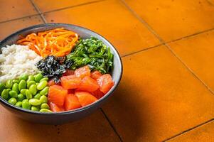 Top view of Poke bowl with Salmon, Edamame and Rice. Orange background. Top view. Copy space photo