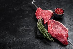 Raw dry aged wagyu picanha barbecue skewer from the cap rump beef with herbs and spices. Black background. Top view. Copy space photo