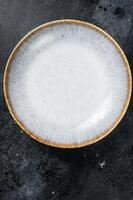 Food cooking background, empty white craft plate on table. Table setting. Black background. Top view. Copy space photo