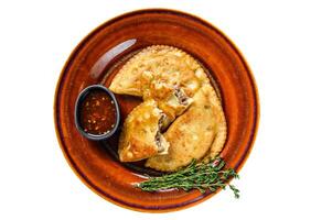Fried empanadas with minced beef meat served on a plate with chili sauce. Isolated on white background. photo
