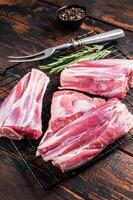 Raw lamb shanks with herbs and spices ready for cooking. Wooden background. Top view photo