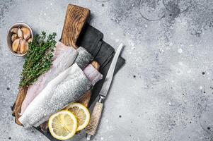 Fresh Raw Sea Bass fillets, Branzino fish with thyme and lemon. Gray background. Top view. Copy space photo