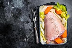 Cooking of Schweinshaxe from Raw pork shank knuckle with vegetables and herbs. Black background. Top view. Copy space photo