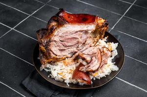 Roast Pork Ham Hock, knuckle with Sauerkraut on a plate. Black background. Top view photo