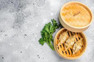Steamed Jiaozi Chinese Dumplings with meat and vegetables in bamboo steamer. grey background. top view photo