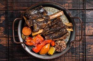 Homemade Braised Lamb Shanks with Sauce and Herbs in a steel tray. Wooden background. Top view photo