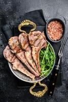 Grilled Lamb mutton Chops steaks in a skillet with green salad. Black background. Top view photo