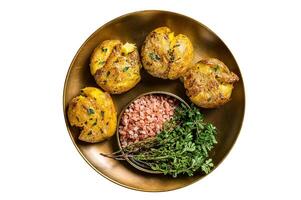 Crushed, smashed potatoes baked with rosemary and thyme on plate. Isolated on white background. photo