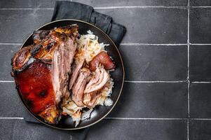 Roast Pork Ham Hock, knuckle with Sauerkraut on a plate. Black background. Top view. Copy space photo