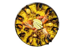 Seafood paella in the fry pan with prawns, shrimps, octopus and mussels. Isolated, white background. photo