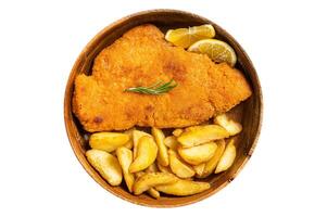 Austrian fried weiner schnitzel with potato wedges in a wooden plate. Isolated on white background. photo