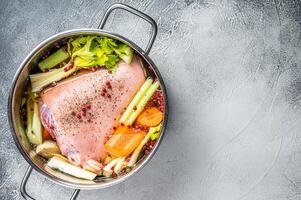 Cooking of Eisbein from Raw pork Hock ham, shank with vegetables and herbs. White background. Top view. Copy space photo