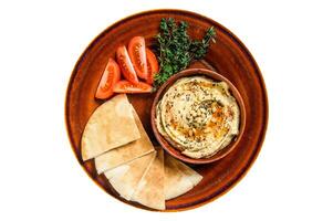 Fresh Hummus with pita bread, tomato and parsley on a rustic plate. Isolated, white background. Top view. photo