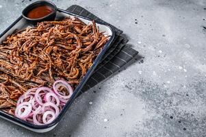 Pulled beef meat with hot chili sauce in baking dish. Gray background. Top view. Copy space photo