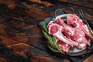 Raw lamb mutton chop steaks, fresh meat cutlets on butcher table. Black background. Top view. Copy space photo