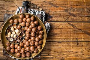 Organic Macadamia nuts in a shell ready to eat. Wooden background. Top view. Copy space photo