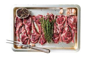 Raw uncooked lamb mutton meat chops steaks with thyme and garlic. Isolated on white background, top view. photo