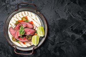 Carne Asada Tacos with grilled steak, green sauce, jalapenos and onion, Mexican food. Black background. top view. copy space photo