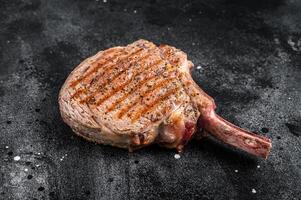 BBQ Grilled Tomahawk beef veal steak on butcher table. Black background. Top view photo