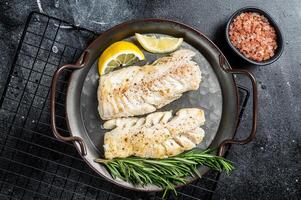 Roast Fillets of codfish, cooked cod fish meat. Black background. Top view photo