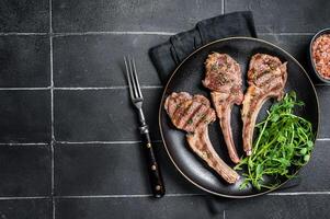 Roasted lamb meat cutlets, mutton chops with garnish. Black background. Top view. Copy space photo