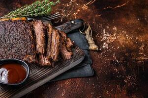 Traditional smoked barbecue wagyu beef brisket on wooden board. Dark background. Top view. Copy space photo