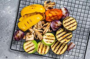 Seasonal summer Grilled vegetables on a grill, bell pepper, zucchini, eggplant, onion and tomato. Gray background. Top view photo