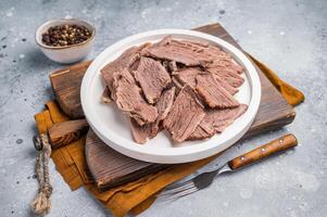 Corned sliced beef meat in a plate. gray background. top view photo