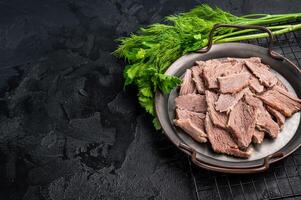 Boiled sliced beef meat in a steel tray. black background. top view photo
