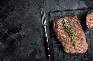 Roasted medium rare flank beef steak with thyme. Black background. Top view. Copy space photo