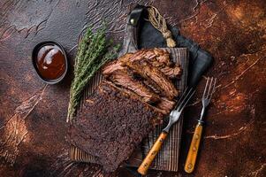 Traditional smoked barbecue wagyu beef brisket on wooden board. Dark background. Top view photo