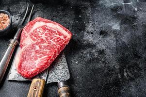 Butcher table with wagyu Rib Eye steak, raw beef meat. Black background. Top view. Copy space photo