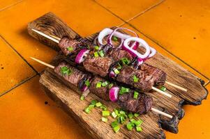 shish brocheta con carne de vaca y Cordero carne, cebolla y hierbas en brochetas naranja antecedentes. parte superior ver foto