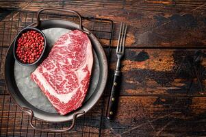 Raw wagyu rib eye beef meat steak in steel tray. Wooden background. Top view. Copy space photo