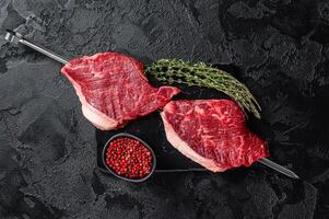 Raw dry aged wagyu picanha barbecue skewer from the cap rump beef with herbs and spices. Black background. Top view photo