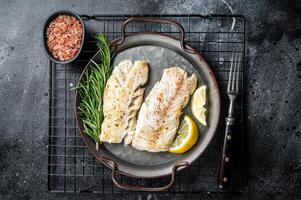 Roast Fillets of codfish, cooked cod fish meat. Black background. Top view photo