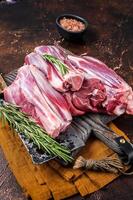 Uncooked Raw lamb mutton shanks on a butcher board. Dark background. Top view photo