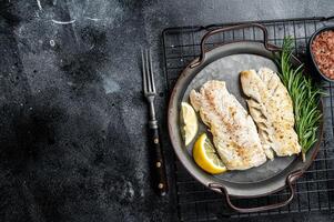 Roast Fillets of codfish, cooked cod fish meat. Black background. Top view. Copy space photo