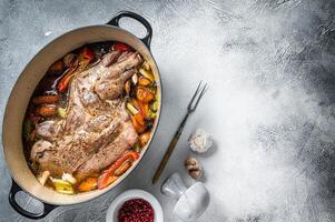 Braised lamb mutton shoulder in a baking dish with vegetables in red wine. White background. Top view. Copy space photo