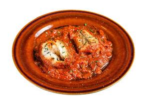 Roast hake white fish fillet with tomato sauce in a plate. Isolated on white background. photo