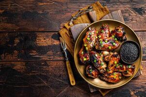 Teriyaki chicken wings with black sesame in a plate. Wooden background. Top view. Copy space photo