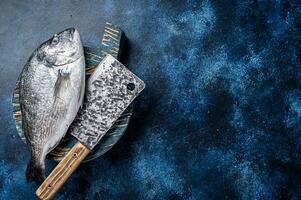 Sea bream or dorado fish on fish market cutting board. Blue background. Top view. Copy space photo